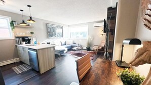 A modern kitchen with a central island, a dining area with a wooden table, and a living space with a sofa and a coffee table.