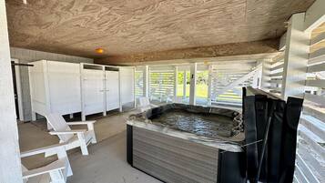 A spa area with a hot tub, wooden ceiling, and white outdoor seating.