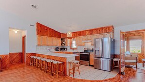 Una cocina moderna con armarios de madera, electrodomésticos de acero inoxidable y una isla central con taburetes de bar.