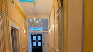 Ein Korridor mit einem Chandelier, einer Tür mit einem Schild und einem gemusterten Boden.