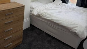 Ein Schlafzimmer mit einem Bett, einem Schminktisch und einem Fenster mit Vorhängen.