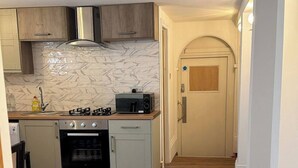 Eine kleine Küche mit Gaskochfeld, Backofen, Mikrowelle und Holzausstattung.