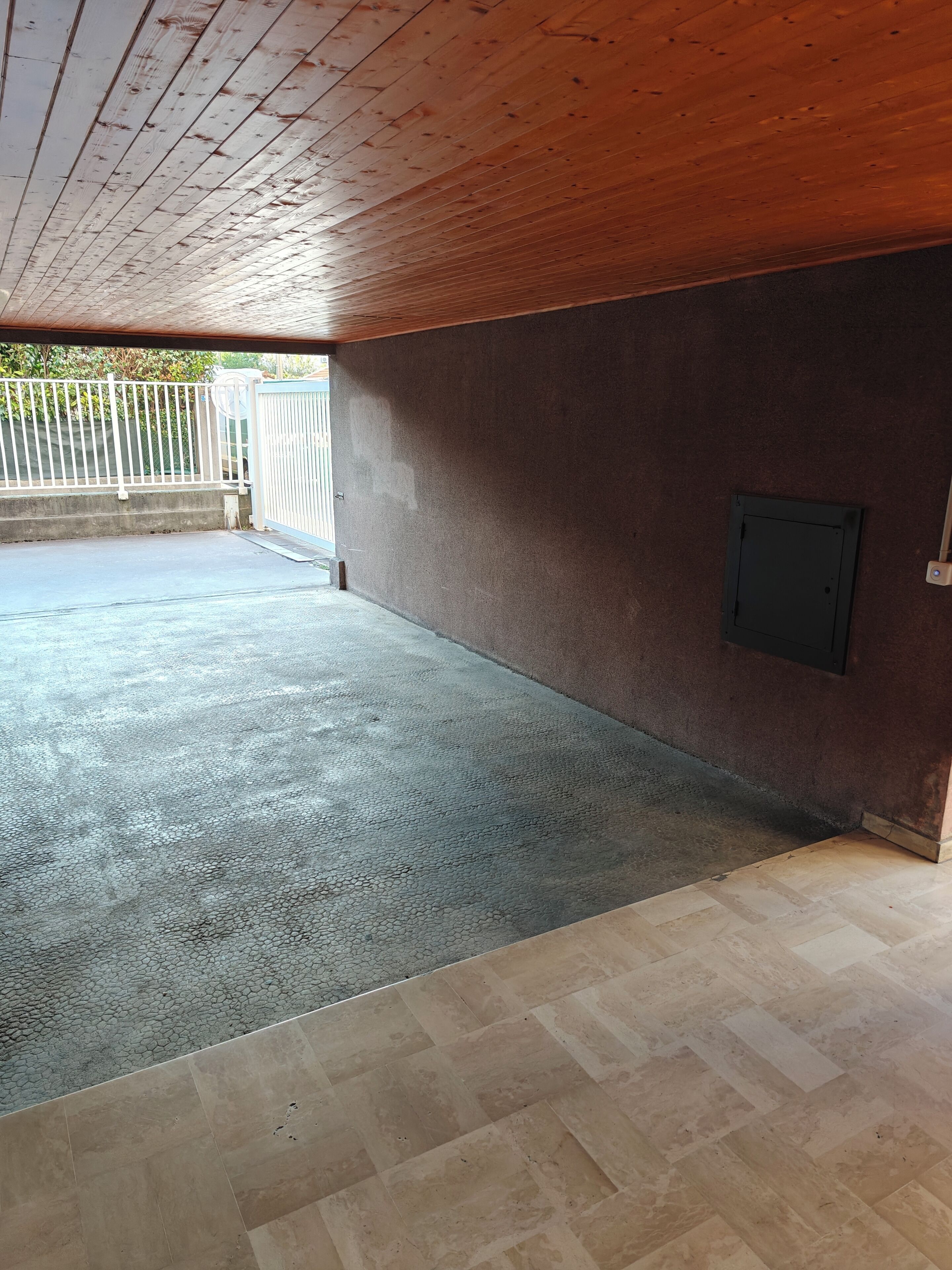 Un espacio interior con suelo de concreto, techo de madera y pared marrón.