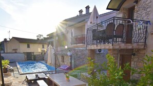 A pool area with a stone deck, outdoor furniture, and a stone building with a balcony. - Spacious Poolside Apartment in Tar (Tar-Vabriga)