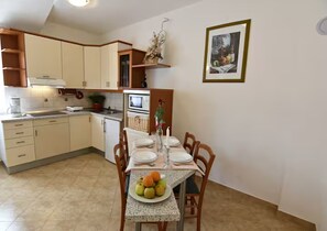 A compact kitchen with a dining area, equipped with basic appliances and a small table set for two. - Spacious Poolside Apartment in Tar (Tar-Vabriga)