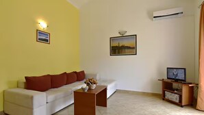 A living room with a sofa, a coffee table, a television on a stand, and two framed pictures on the wall. - Spacious Poolside Apartment in Tar (Tar-Vabriga)