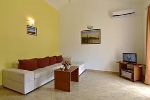 A living room with a sofa, a coffee table, a television on a stand, and two framed pictures on the wall. - Spacious Poolside Apartment in Tar (Tar-Vabriga)