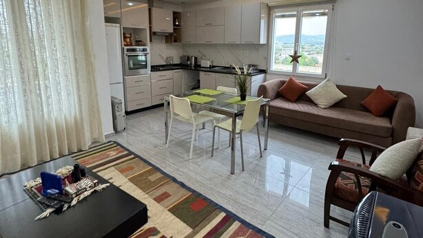 Ein modernes Wohnzimmer mit Essbereich, Küche und einem großen Fenster.