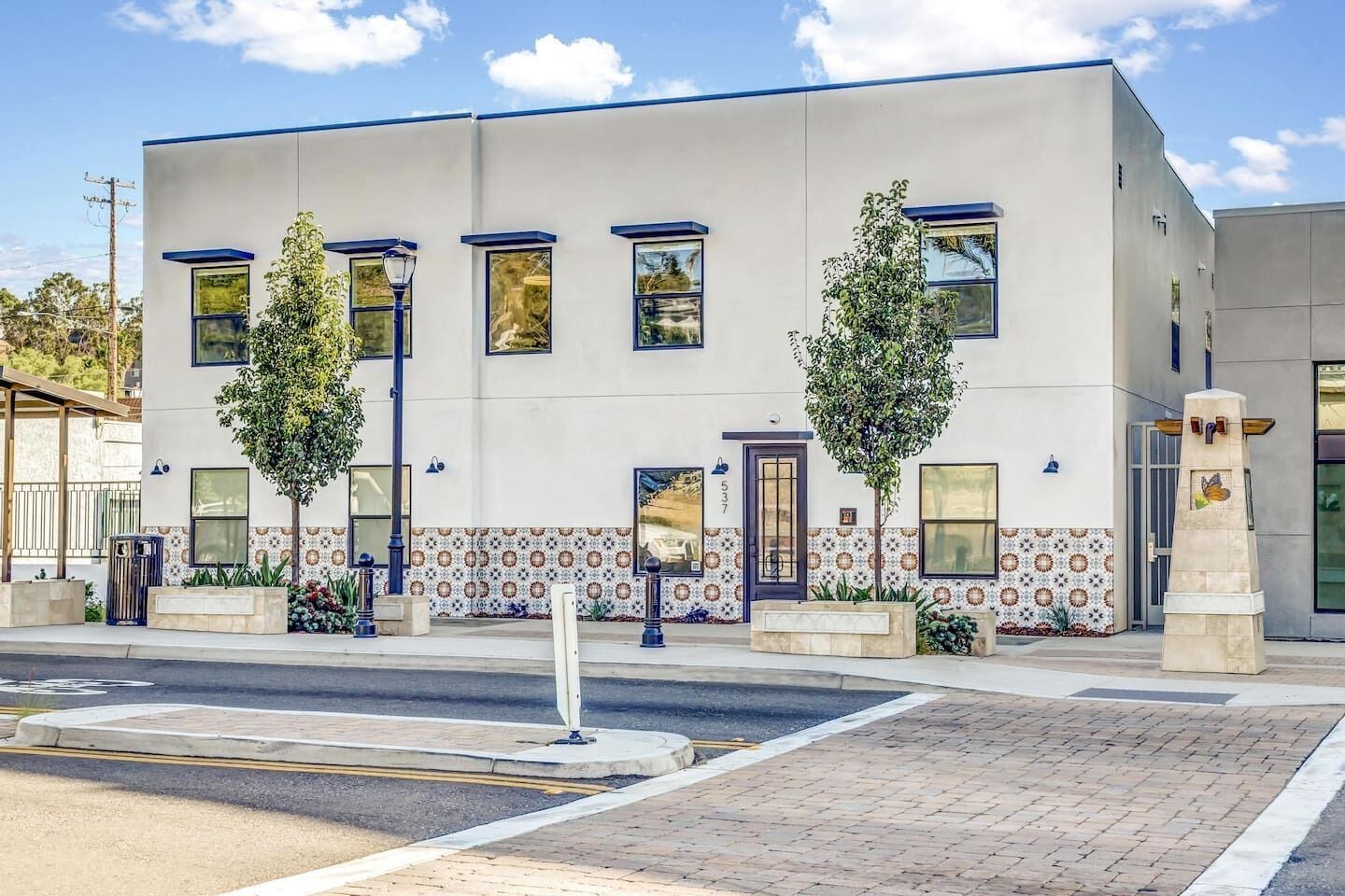 Ein modernes Gebäude mit flacher Fassade, großen Fenstern und einer gefliesten Erdgeschosszone.