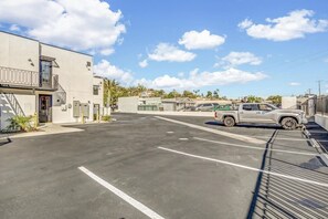 A parking lot with a single SUV, buildings with balconies, and a clear sky.