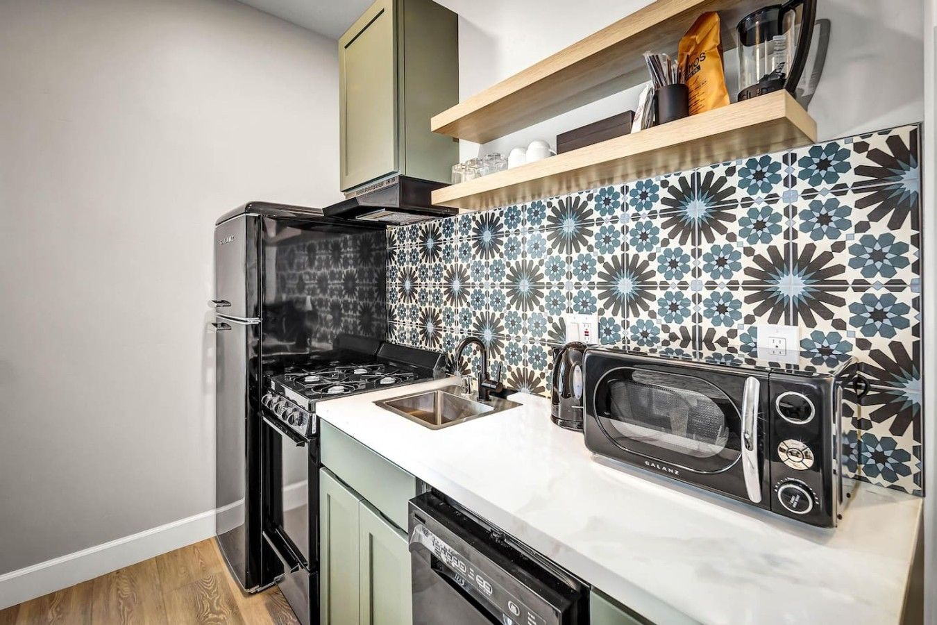 A compact kitchen with a black stove, a microwave, and a sink.