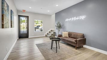 A modern interior with a brown leather sofa, a small round table, and a staircase leading to an upper level.