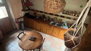 Une cuisine rustique avec une table en bois, un porte-ustensiles suspendu et un mur recouvert de carreaux.