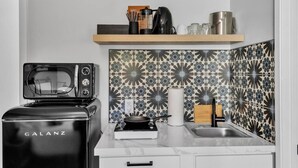 Una cucina con un tostapane Galanz, un bollitore, un lavandino e uno schienale decorato.