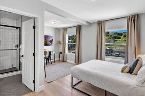 Quarto moderno com cama, escrivaninha e vista para o exterior.