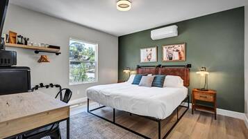Une chambre à coucher avec un lit, une table de chevet, une lampe et une fenêtre donnant sur un beau paysage.