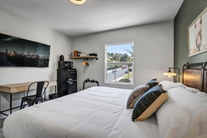 A hotel room with a bed, desk, chair, and a window with a view of the street. - Family Escape | Legoland 15 Min | Wave 10 Min (Vista)