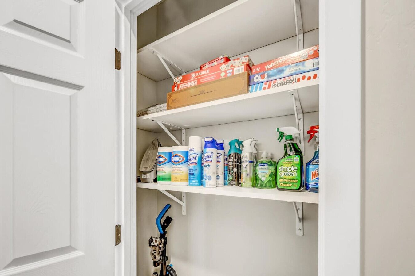A storage closet with shelves containing cleaning supplies and a vacuum cleaner.