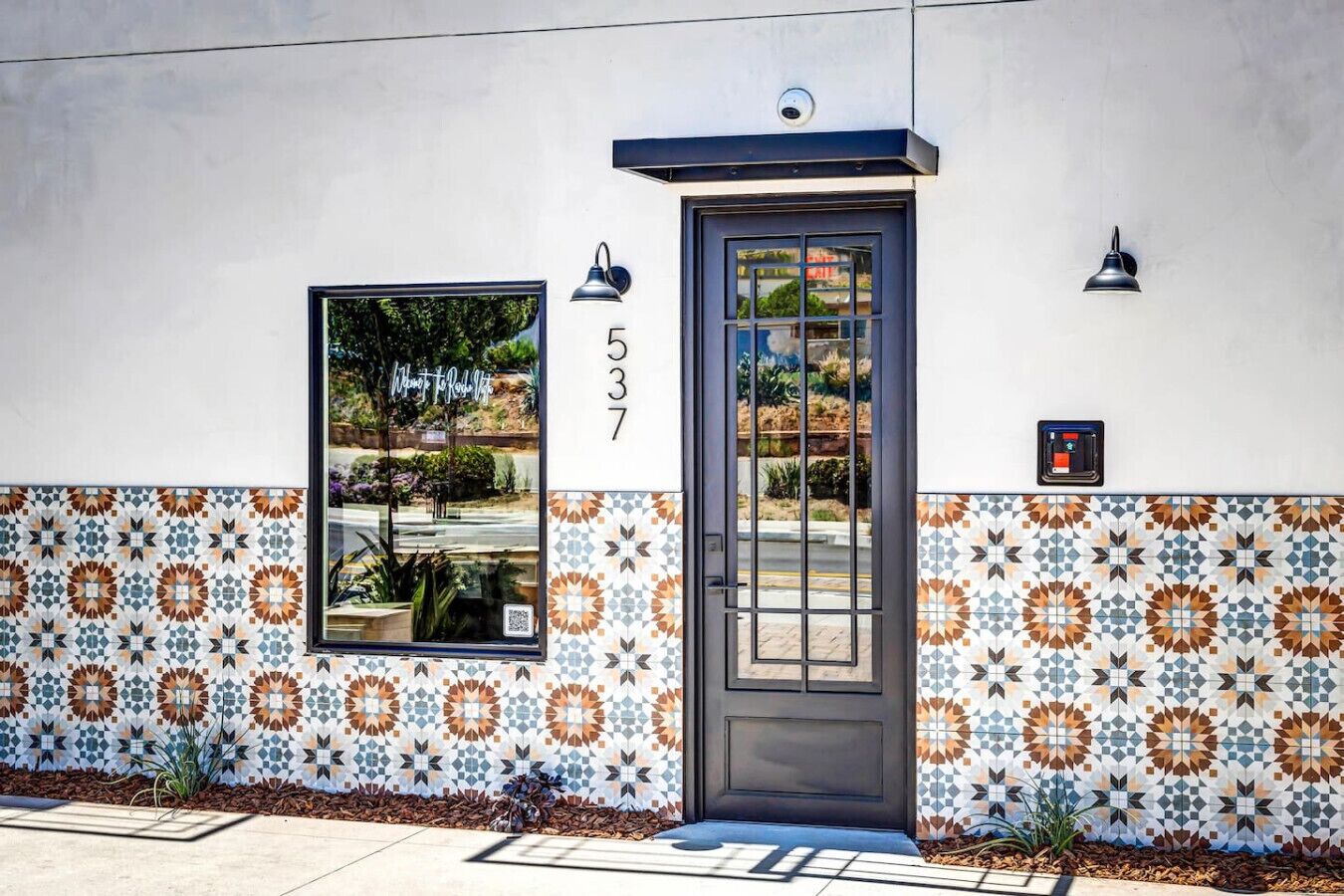 Fachada de edificio con una puerta numerada, una ventana y azulejos con diseño.