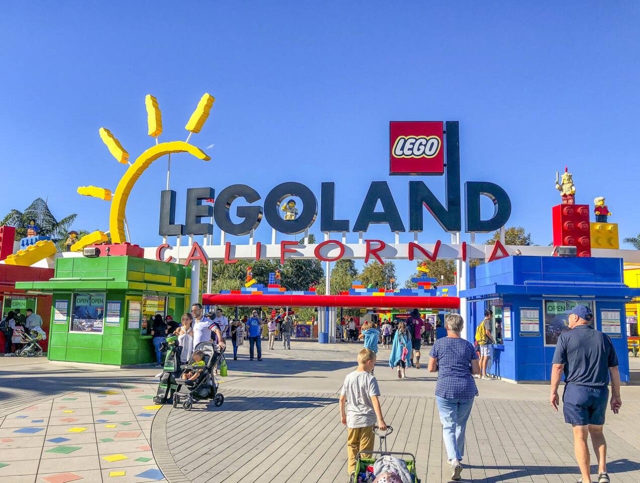 Een entree met een LEGO-thema, met een groot bord, een speelruimte en een houten looppad.