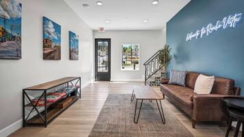 A modern lobby with a sofa, a coffee table, a bookshelf, and a wall with a neon sign.