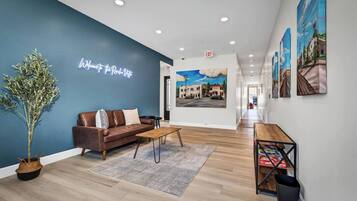 A hotel lobby with a blue accent wall, a brown leather sofa, a wooden coffee table, and a reception desk.