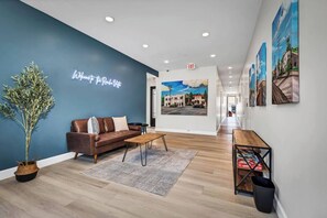 A hotel lobby with a blue accent wall, a brown leather sofa, a wooden coffee table, and a reception desk. - Vibrant Vista Stay, Short Stroll To Downtown (Vista)