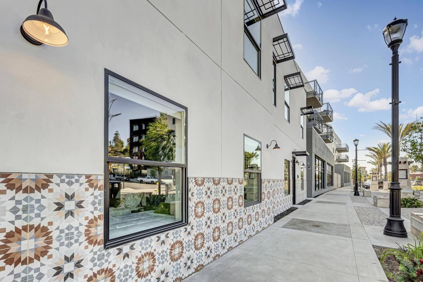 A modern building with large windows, a patterned tile border, and outdoor lighting.