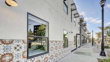 A modern building with large windows, a patterned tile border, and outdoor lighting.