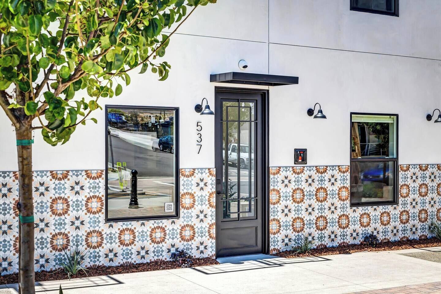 Fachada de edificio con un número, una puerta y baldosas estampadas.