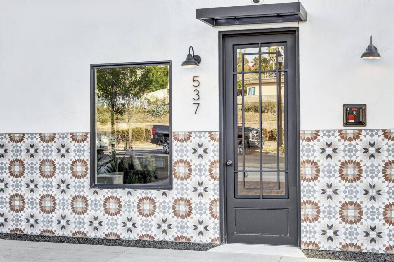 Un immeuble avec un numéro de rue, une porte dotée d’une fenêtre et des carreaux muraux décorés.