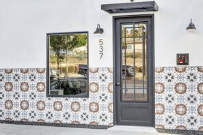 Un edificio con un número y una puerta con ventanal, además de baldosas decorativas en la pared.