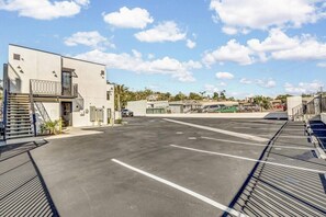 A parking area with marked spaces, a building with a balcony, and a clear sky. - Vista Hideaway | Downtown & Beaches Nearby (Vista)
