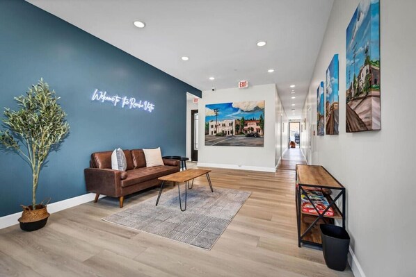 A hotel lobby with a blue wall, a brown leather sofa, a wooden coffee table, and a small potted plant.