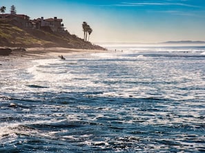 A coastal beach with waves, a clear sky, and a hillside with buildings. - Vista Hideaway | Downtown & Beaches Nearby (Vista)
