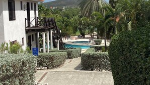Een resort met een zwembad, palmbomen en een gebouw met een rode dakbedekking.