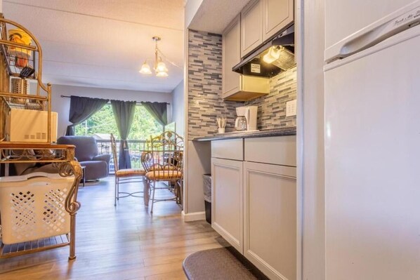 A compact kitchen with a refrigerator, a coffee maker, and a microwave. There is a dining area with a table and chairs. - OLDE GATLINBURG RANTEL (Gatlinburg)