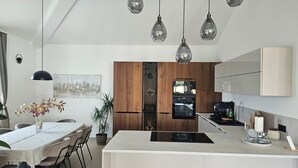 A modern kitchen with a central island, wooden cabinetry, and pendant lighting. - New Elegant Luxury Villa Viktoria in Historic Pula (Pula)