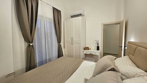 A bedroom with a bed, a wardrobe, a bedside table with a vase, and an air conditioning unit. - New Elegant Luxury Villa Viktoria in Historic Pula (Pula)
