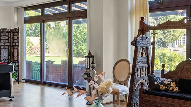 A spacious room with a glass coffee table, a wooden sofa, and a large window with a view of greenery. - 6 bedroom spacious house minutes from Wembley Stadium (Wembley)