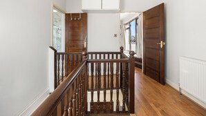 A wooden staircase with a railing, a white ceiling, and a door leading to another room. - 6 bedroom spacious house minutes from Wembley Stadium (Wembley)