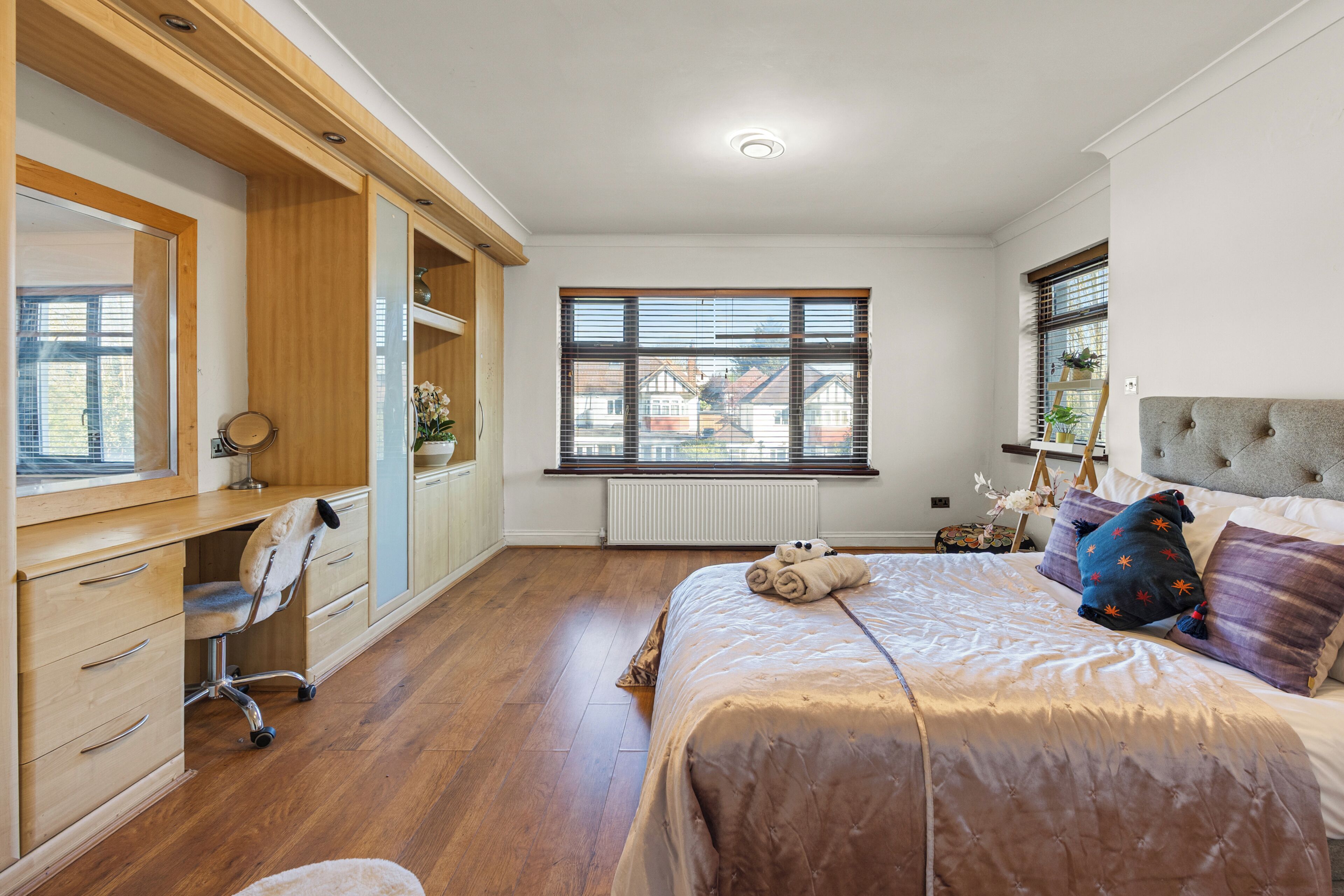 Une chambre à coucher avec un lit, un bureau, une chaise et une fenêtre avec des stores.