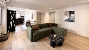Una sala moderna con un sofá modular, una mesa de centro redonda y un comedor al fondo.