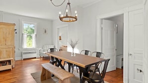 A dining room with a wooden table, chairs, a bench, a chandelier, and a view of the outdoors. - Charming Hudson Farmhouse with Fire Pit (Hudson)