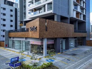 Um edifício moderno com um destaque para a placa 'Solaz', amplas janelas de vidro e um telhado plano.