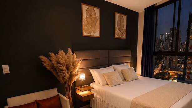 Een moderne slaapkamer met een groot bed, een nachtkastje, een lamp, een sofa en uitzicht op de stad 's nachts.
