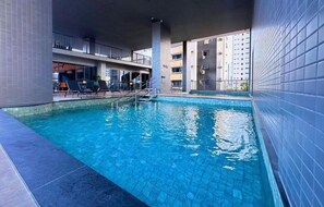An indoor swimming pool with tiled walls and a clear blue pool. - Premium Studio with Ocean View in Manaíra. (João Pessoa)