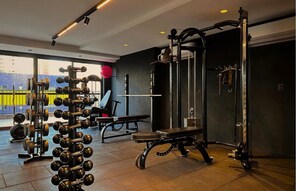A gym with weightlifting equipment, a bench, and a squat rack. - Premium Studio with Ocean View in Manaíra.  (João Pessoa)