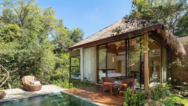 A modern house with a pool, wooden deck, and glass doors leading to a dining area.