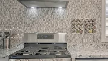 Cozinha com fogão de aço inoxidável, painel de controle digital e backsplash com azulejos quadrados.